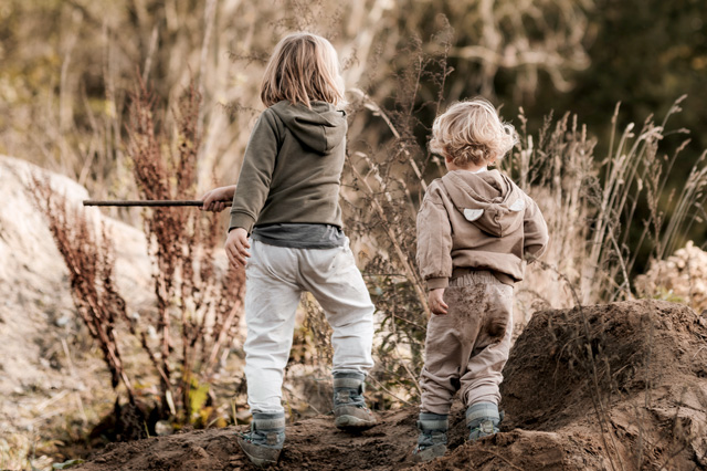 Zwei Kinder spielen draußen und erkunden neugierig die Welt – Bonusmodul „Groß werden, klein bleiben“ im Bindungskurs von Sichtwechsel.