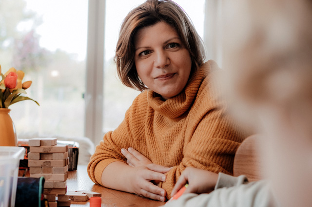 Katharina von Sichtwechsel sitzt am Tisch und spricht mit ihrem Kind – Bindungskurs Modul: Gewaltfreie Kommunikation